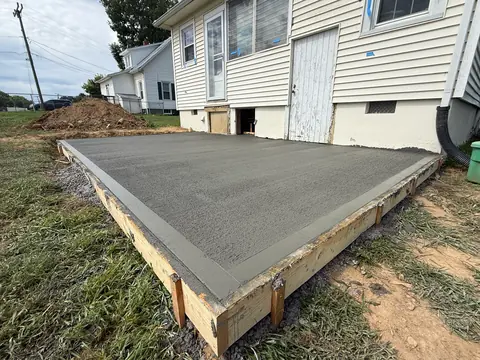 Finished concrete slab in timber forms against the back of a house.