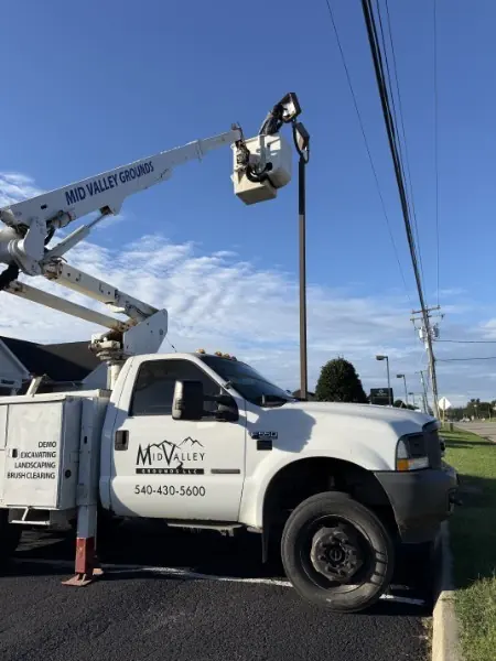 Mid Valley Grounds bucket truck with the boom raised beside a street light.